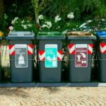 a row of trash cans sitting on top of a sidewalk